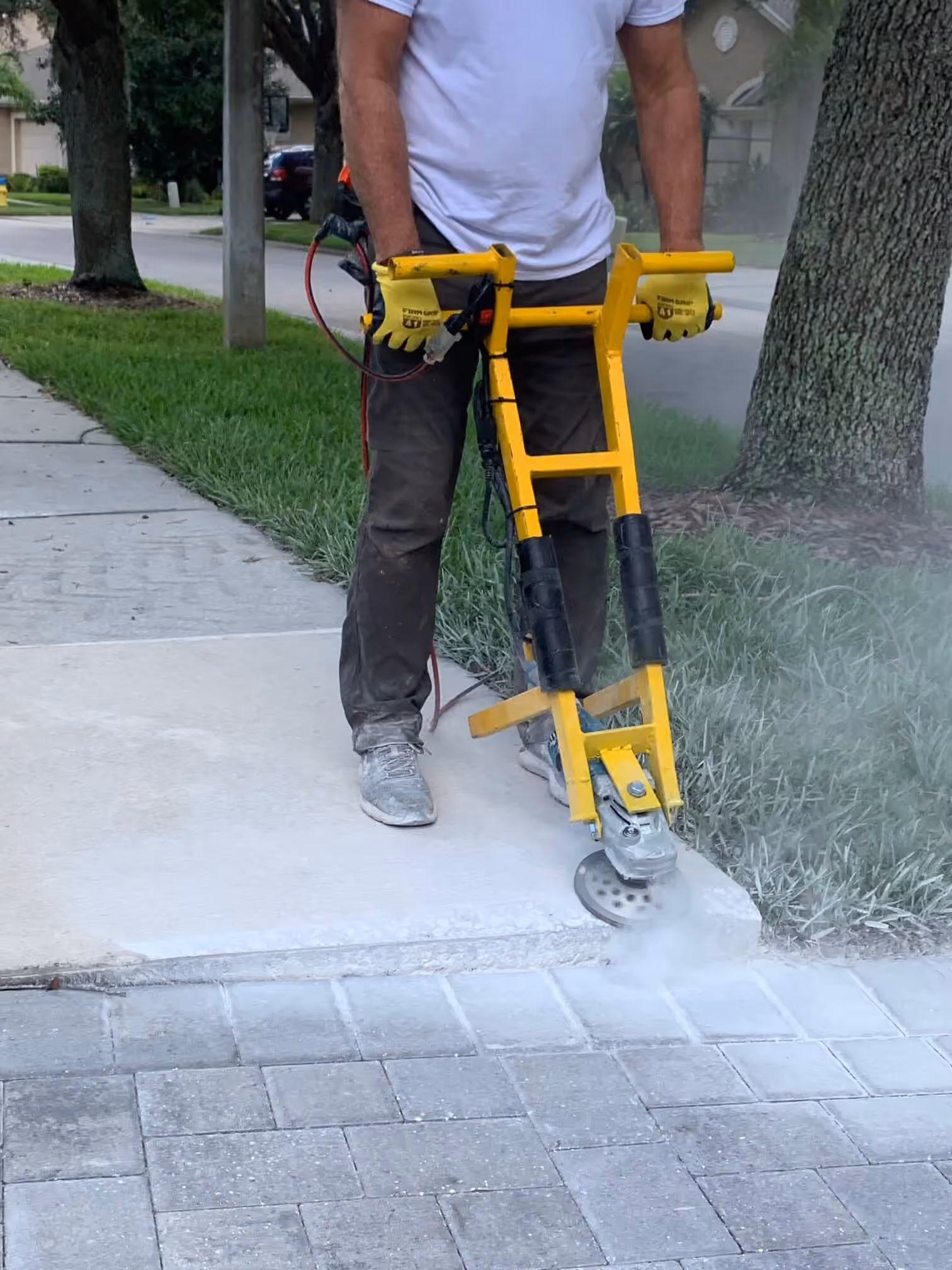 Technician grinding the edge of a raised sidewalk slab