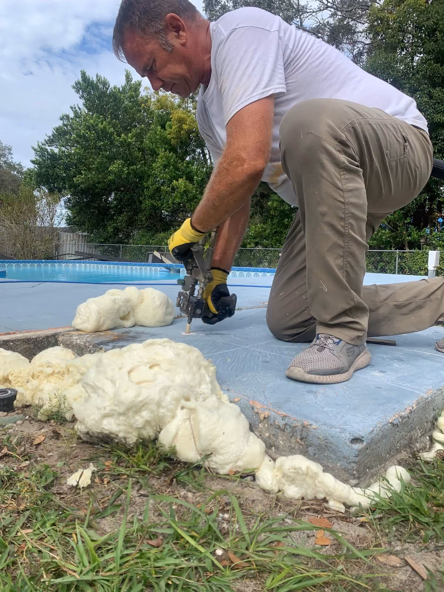 Technician injecting polyurethane foam under a pool deck slab