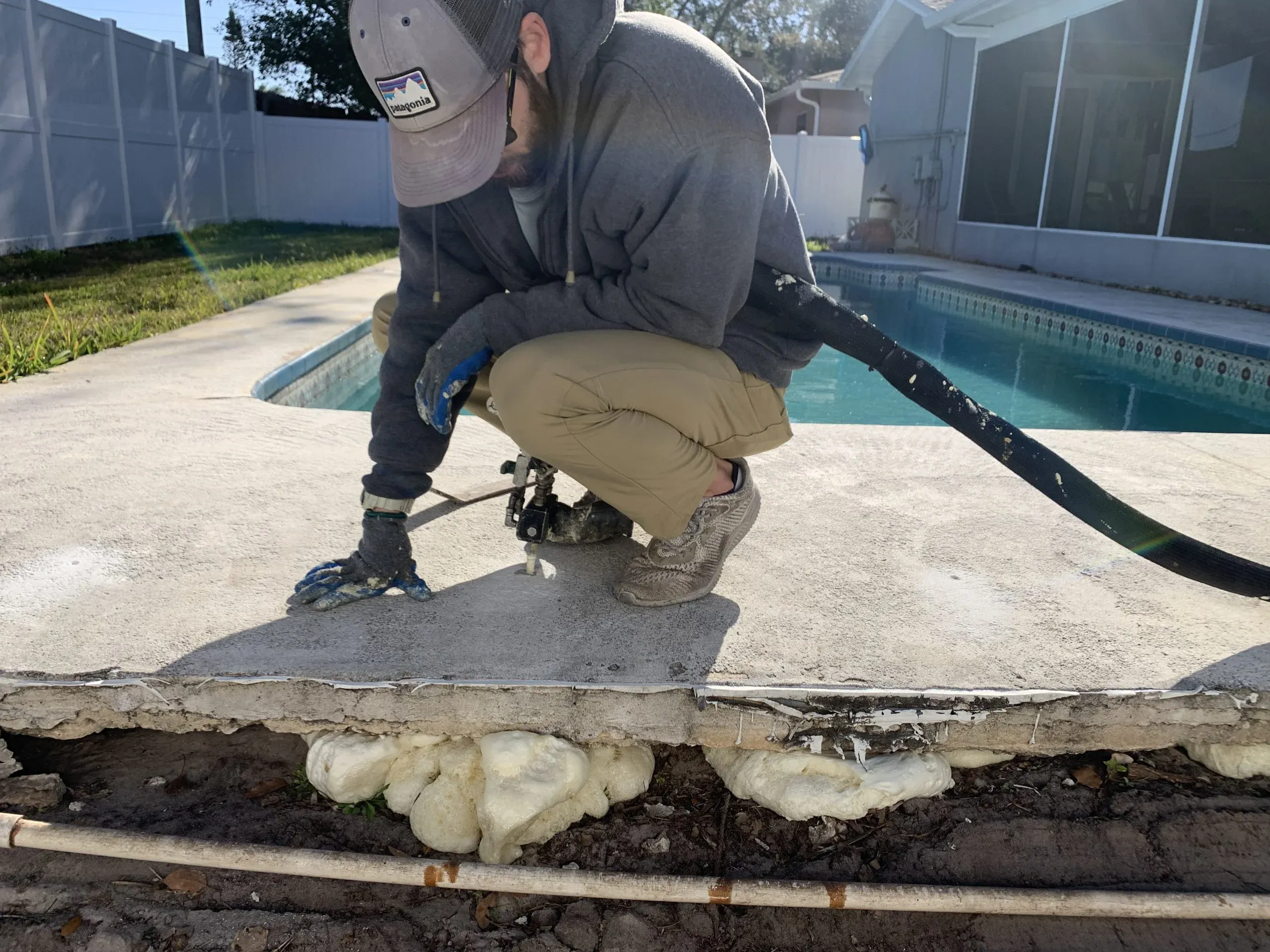 Technician injecting polyurethane foam under a pool deck slab
